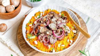 Vegan stamppot. Foto: Leukerecepten.nl Een wit bord met daarin oranjegekleurde stamppot, met als topping rode ui, champignons en gehakte nootjes.
